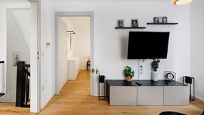 Un salon moderne avec un téléviseur à écran plat, une console et un luminaire suspendu.