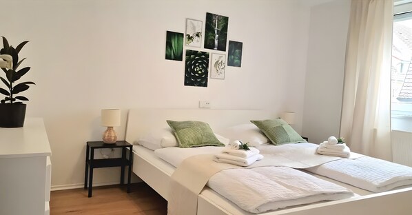A bedroom with a bed, pillows, a nightstand, a lamp, and wall art.