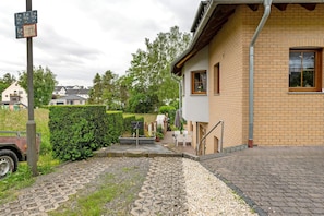 En boligbygning med en belagt indgang, et lille udendørs siddeområde og en synlig postkasse.