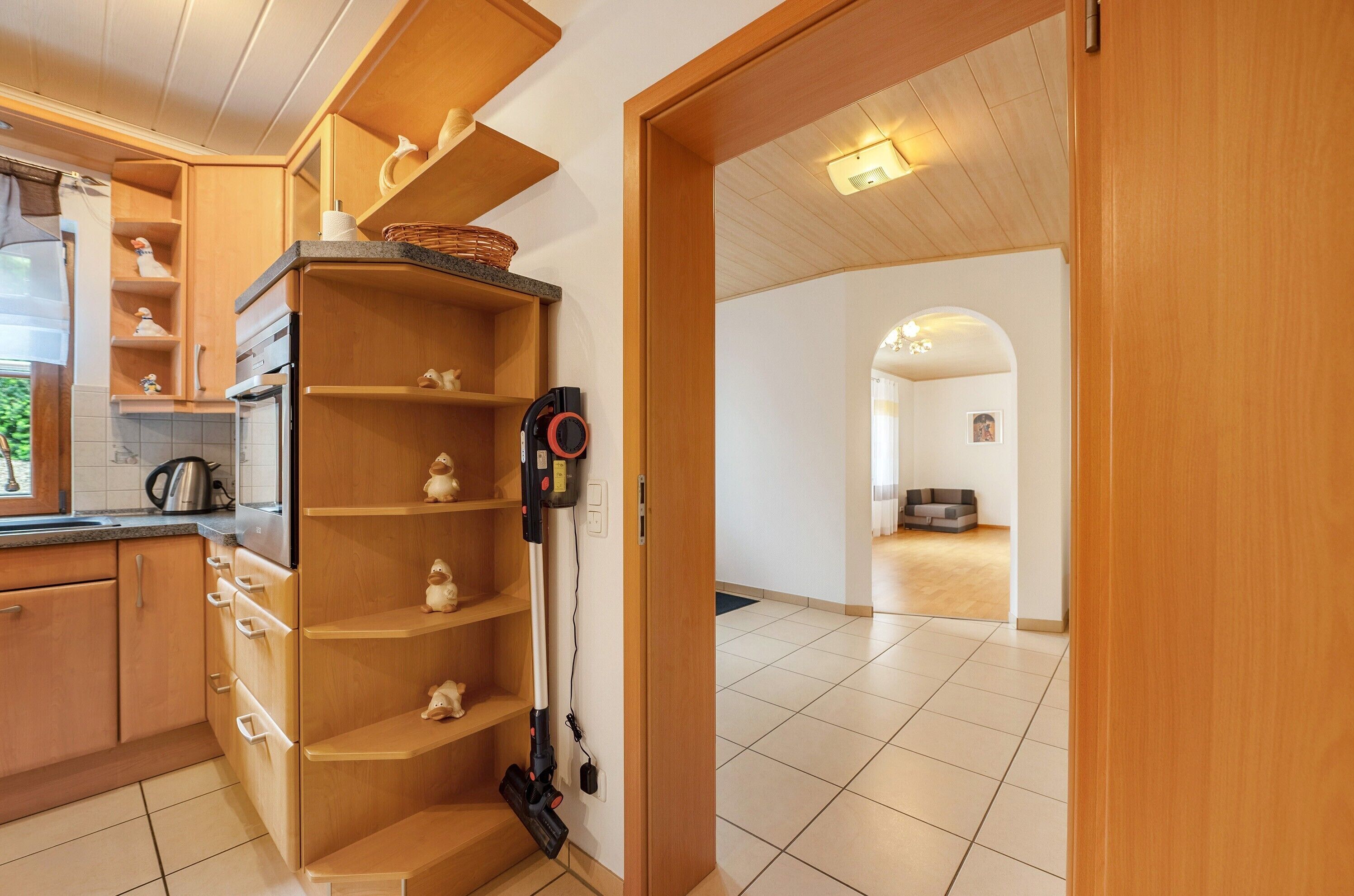 Eine moderne Küche mit Holzschränken, einem eingebauten Backofen und einem Staubsauger.