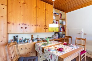 Ett kök med träinredning, ett matbord, stolar och en hängande lampa.