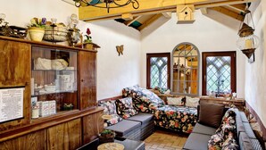 Ein gemütliches Zimmer mit einem Holzkasten, einem blumigen Sofa und einer Chandel.