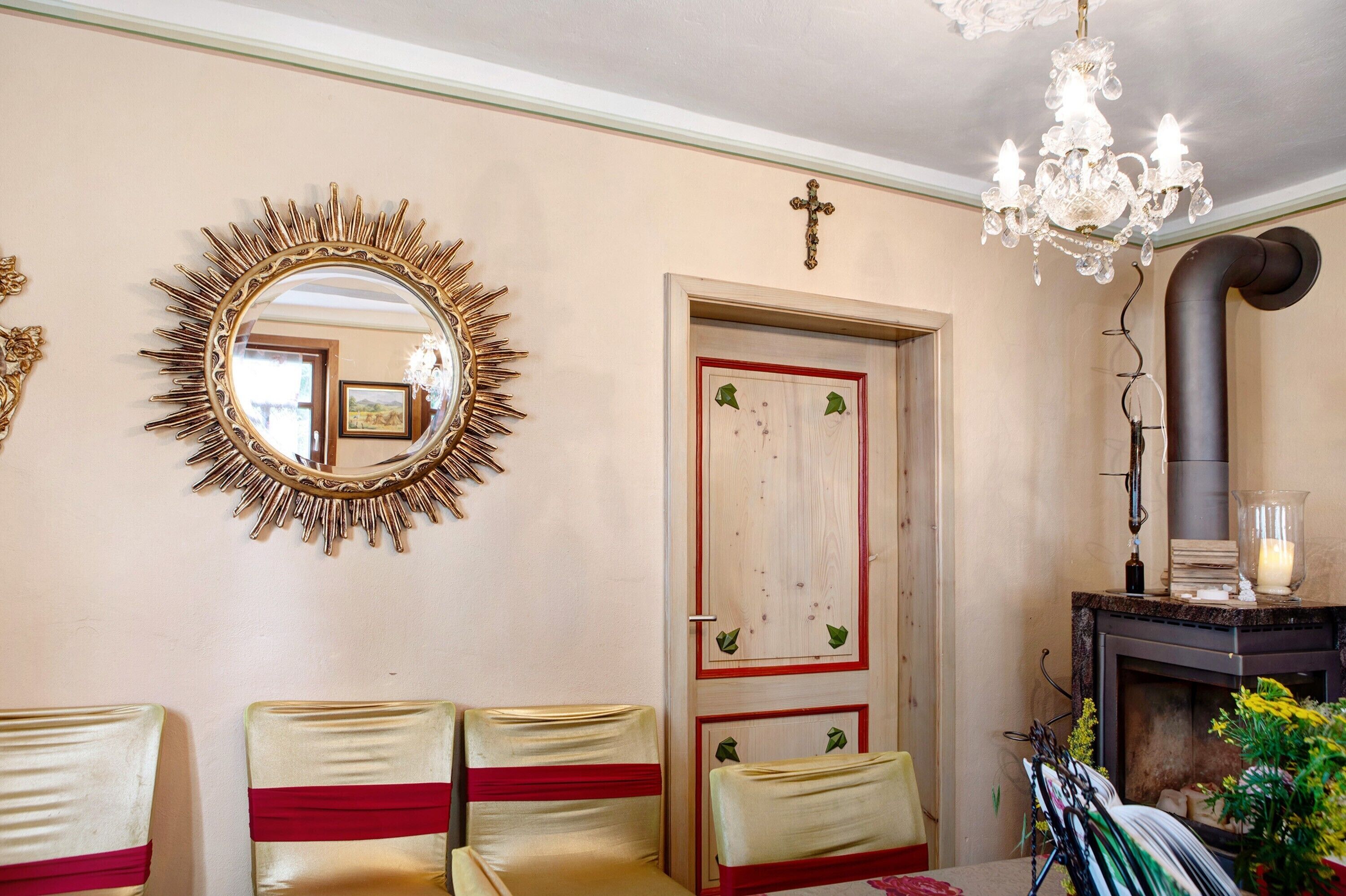 A room with a mirror, a chandelier, a door with decorative elements, and a fireplace.