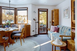Ein gemütliches Zimmer mit Esstisch, Stühlen, einer Couch und einem Bücherregal.
