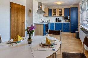 A modern kitchen with blue cabinets, a microwave, and a stove.