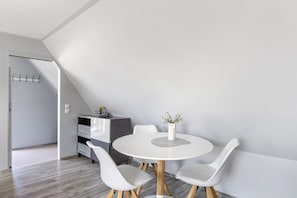 Un espace repas moderne avec une table ronde, des chaises blanches et un vase rempli de fleurs.