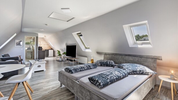 Une chambre de style loft moderne, dotée d’un grand lit, d’un bureau et d’un coin repas.
