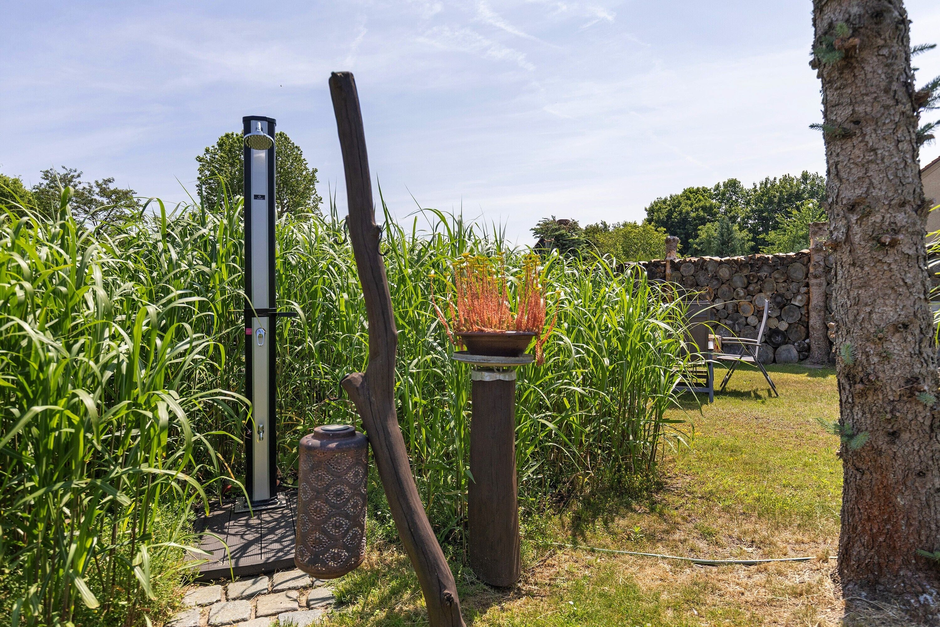 A garden with a tall metal structure, a wooden post, and a stone wall.