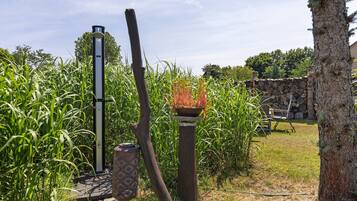 A garden with a tall metal structure, a wooden post, and a stone wall.