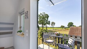 Un balcon avec une table et des chaises, un pot de fleurs et une vue sur la campagne.