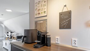 Une cuisine moderne équipée d’une machine à café, d’une bouilloire et d’un panneau affiché sur le mur.