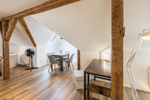Quarto de loft moderno com vigas de madeira aparentes, claraboia, janela grande, escrivaninha e cadeira.