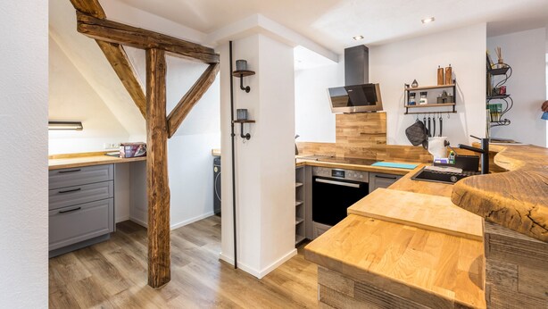 A modern kitchen with wooden beams, built-in shelves, and a central island.