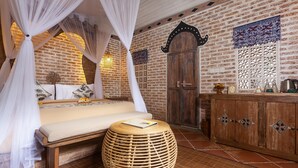 A bedroom with a bed, a round wooden ottoman, a wardrobe, and a decorative wall panel. - Sacred Canyon Ubud by GenuineHost (Payangan)