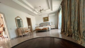 Une chambre spacieuse avec un grand lit, une commode, une coiffeuse et un ventilateur de plafond.