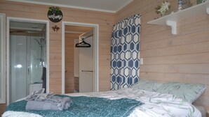 Une chambre avec un lit, une douche, une armoire et un panneau d’accueil.