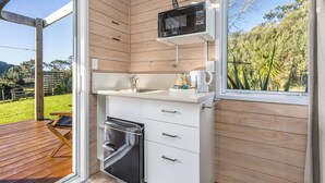 Une cuisine compacte équipée d’un four à micro-ondes encastré, d’un évier et d’un petit réfrigérateur.
