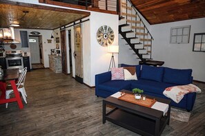 A spacious living area with a blue sofa, a coffee table, and a kitchen in the background.