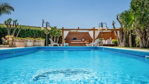 Una piscina con sillas de descanso y un área de estar techada.