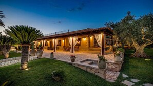A villa with a covered patio, outdoor seating, and a well-maintained garden. - Villa Cutrera 6 Emma Villas (Chiaramonte Gulfi)