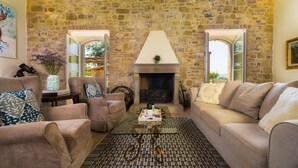 A cozy living room with stone walls, a fireplace, and comfortable seating. - Villa Flaminia 8 2 - Emma Villas (Gualdo Cattaneo)