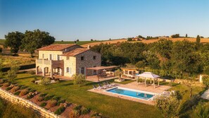 Une villa en pierre dotée d’une piscine, d’un espace salon extérieur et d’un jardin.