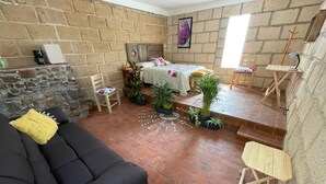 A cozy room with a bed, a sofa, and a small table. There are potted plants and a window providing natural light. - La Posada de Don Luis (Ezequiel Montes)