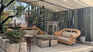 An outdoor patio with wicker furniture, a glass-top table, and a stone planter. - La Posada de Don Luis (Ezequiel Montes)