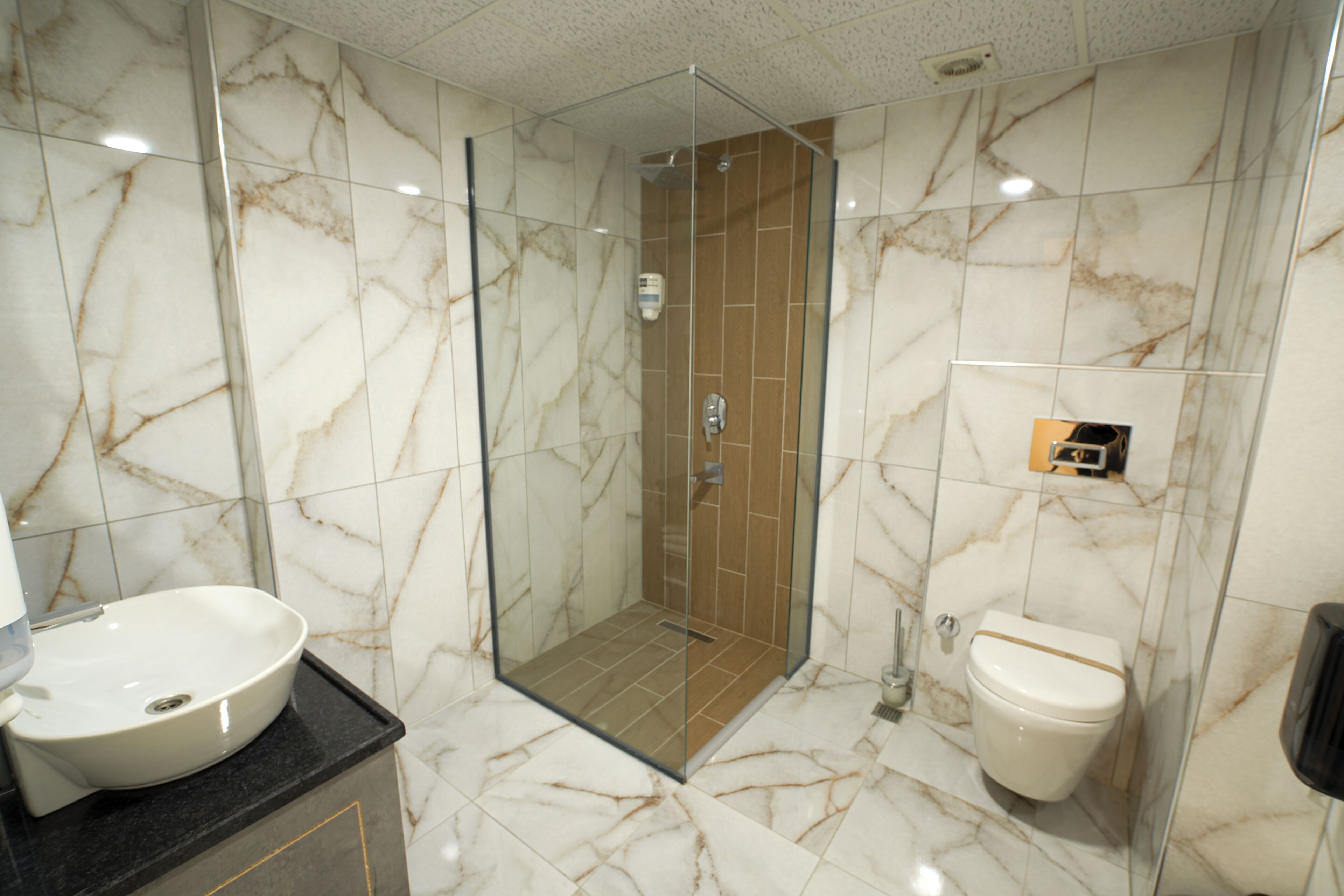 A bathroom with a glass-enclosed shower, a white sink, and a toilet.