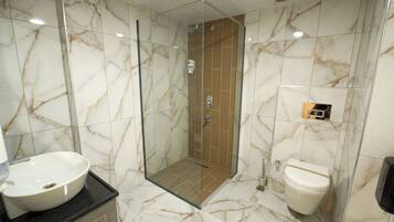 A bathroom with a glass-enclosed shower, a white sink, and a toilet.