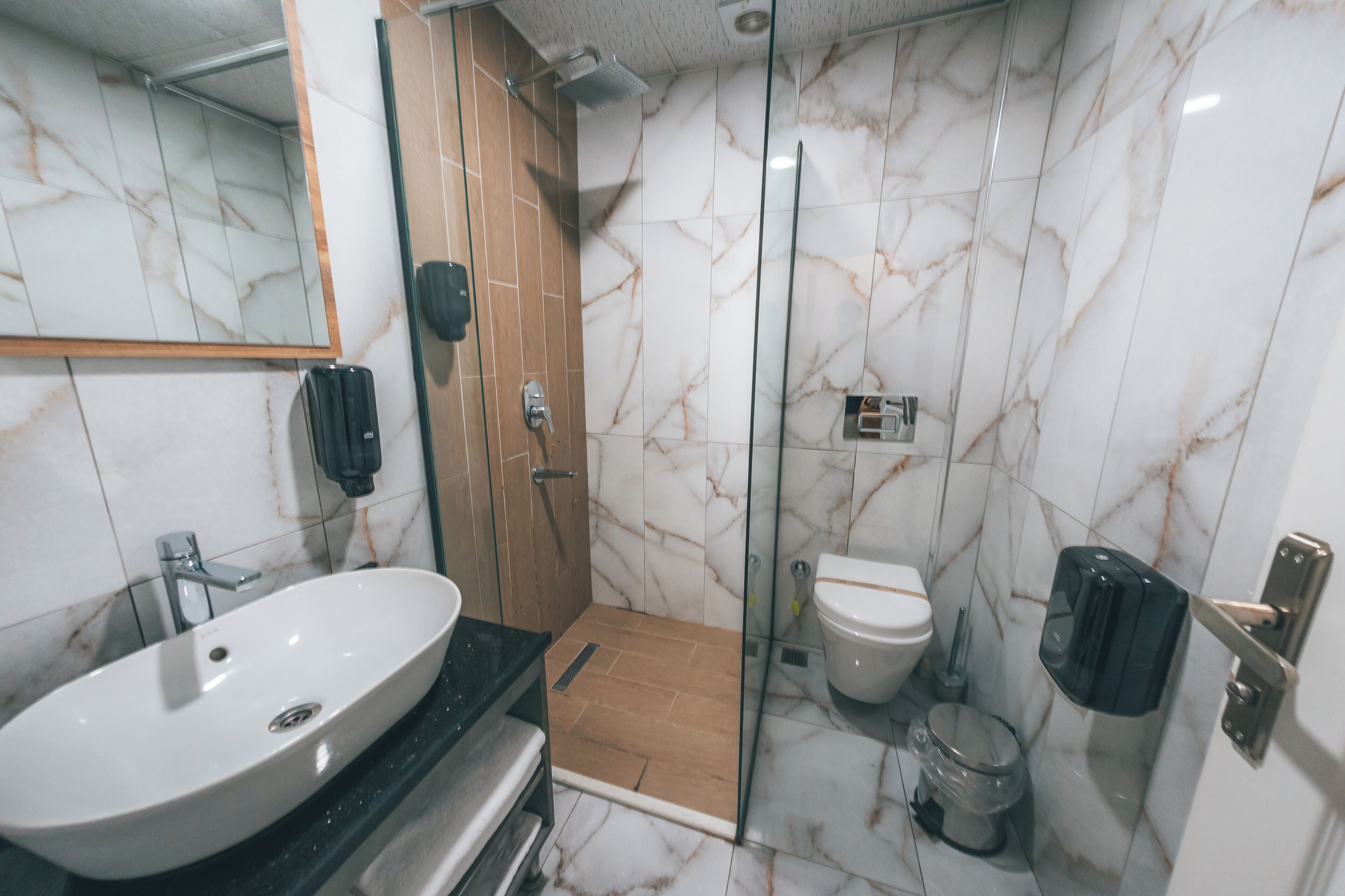 Un baño moderno con ducha de mármol, inodoro y lavabo.