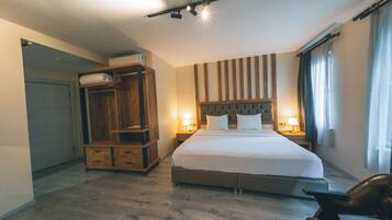 Une chambre d’hôtel avec un grand lit, une armoire en bois, des lampes de chevet et une fenêtre avec des rideaux.