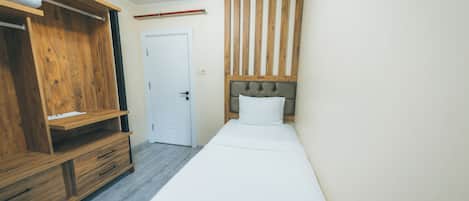 Un dormitorio con un armario de madera, una cama con cabecera y una puerta blanca.