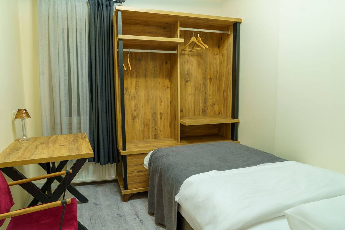 Un dormitorio con un armario de madera, una mesita y una cama.