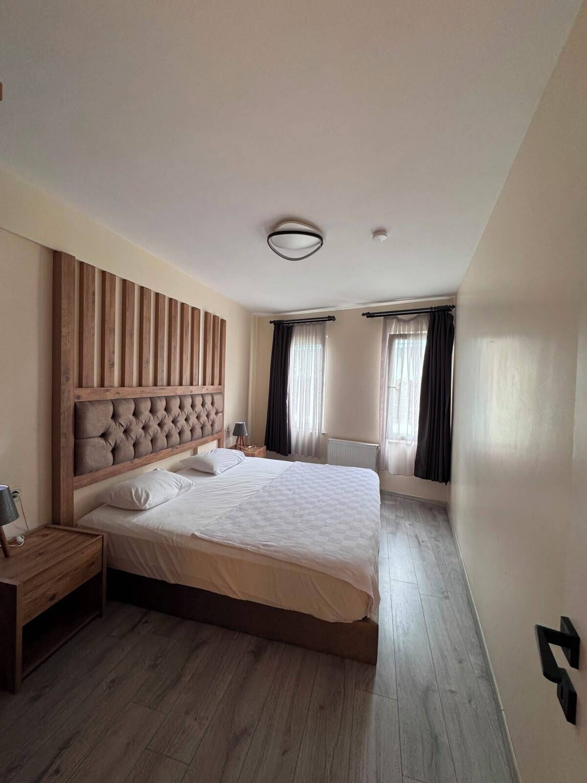 A bedroom with a large bed, a wooden headboard, a bedside table, and a nightstand.