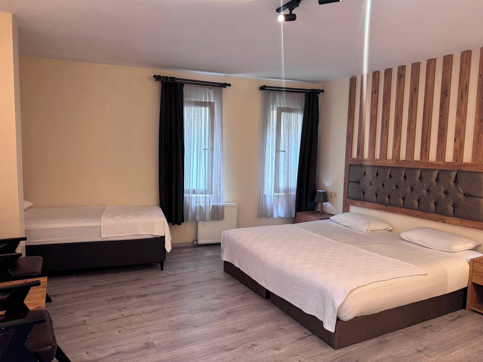 Una habitación de hotel con dos camas, un cabecero de madera, una silla de masaje y una camilla de masaje.