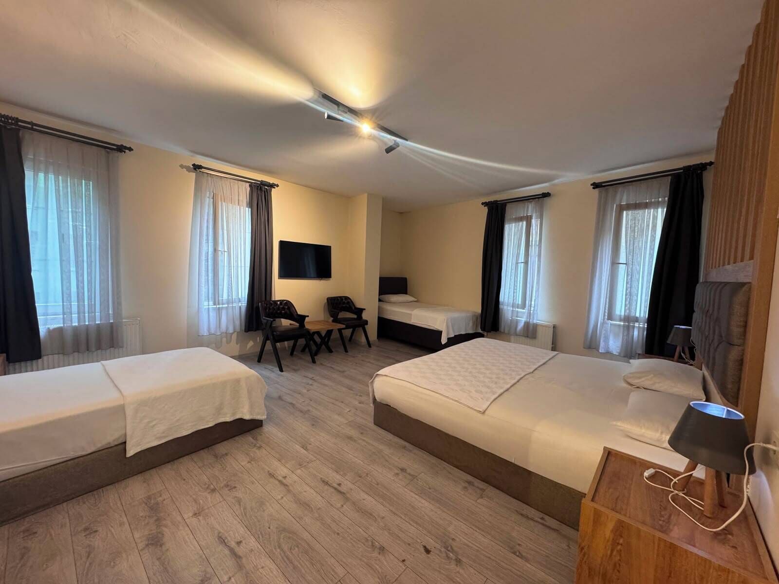 Een hotelkamer met twee eenpersoonsbedden, een bureau met stoel, een televisie en een lamp.