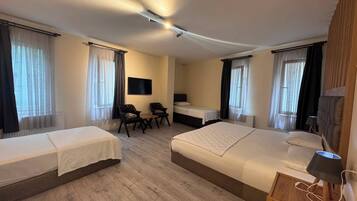 Een hotelkamer met twee eenpersoonsbedden, een bureau met stoel, een televisie en een lamp.