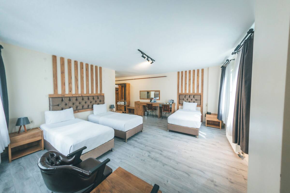 A hotel room with two beds, a desk, and a chair.