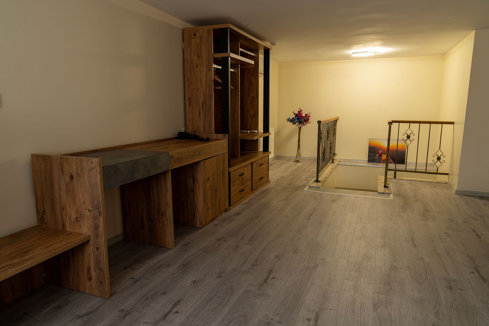 Ein Zimmer mit einem Holztisch, einem Kleiderschrank, einer Bank, einem kleinen Tisch und einem Geländer.