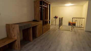 Ein Zimmer mit einem Holztisch, einem Kleiderschrank, einer Bank, einem kleinen Tisch und einem Geländer.