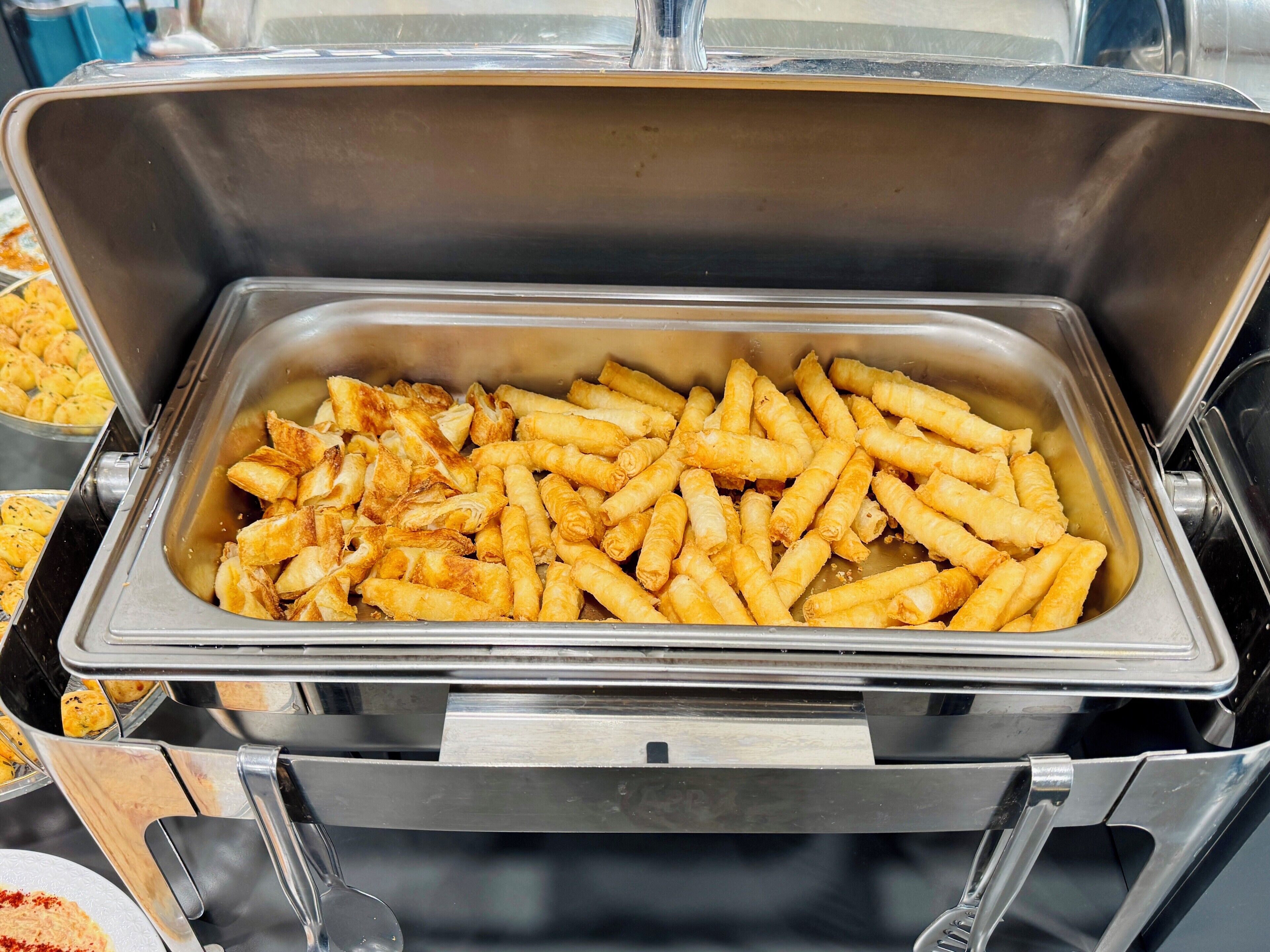Un bufé con diversas opciones de comida frita, incluyendo papas fritas y otros platillos.