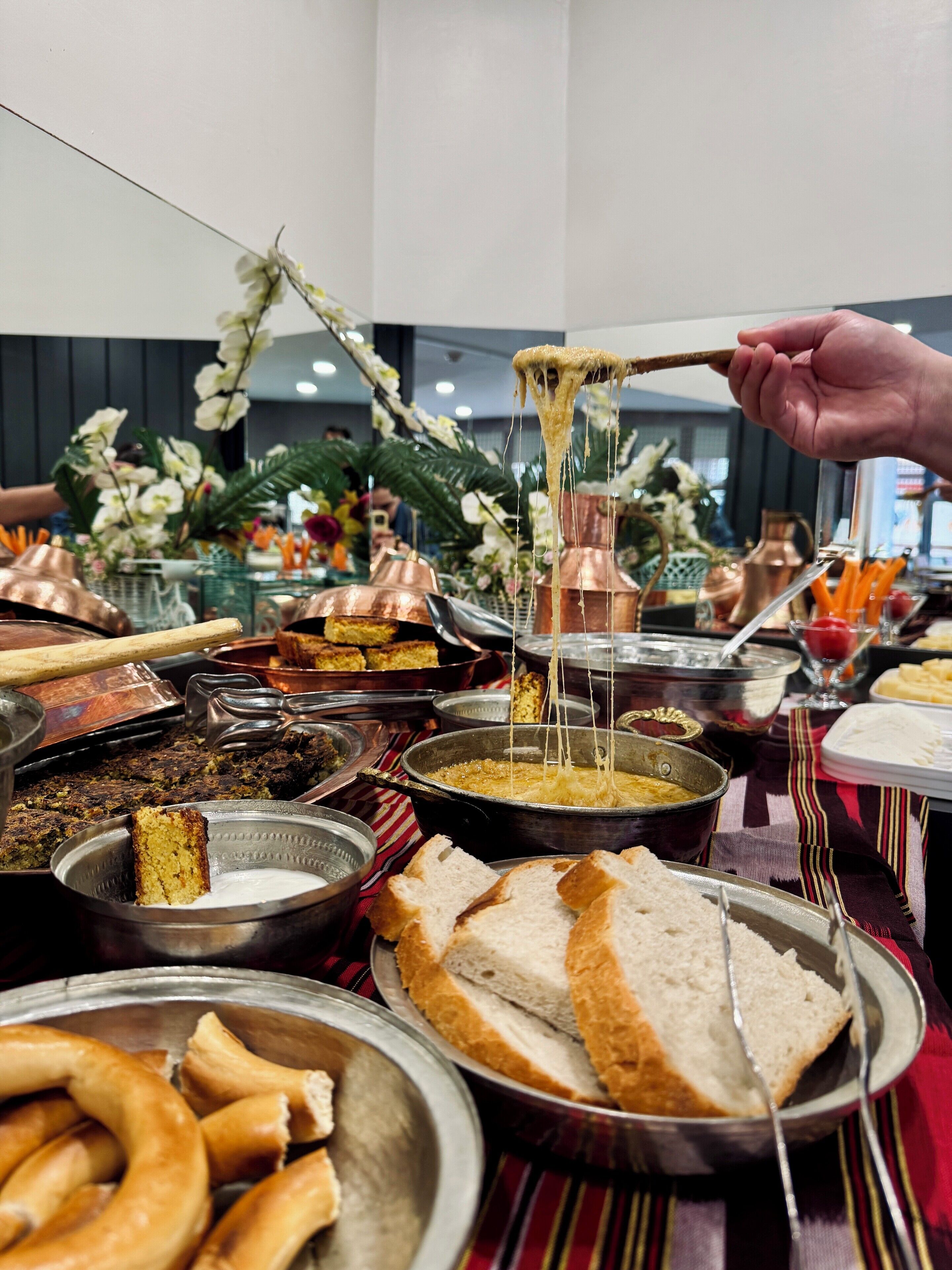 A buffet with various dishes, including bread, pastries, and a cheese dish.