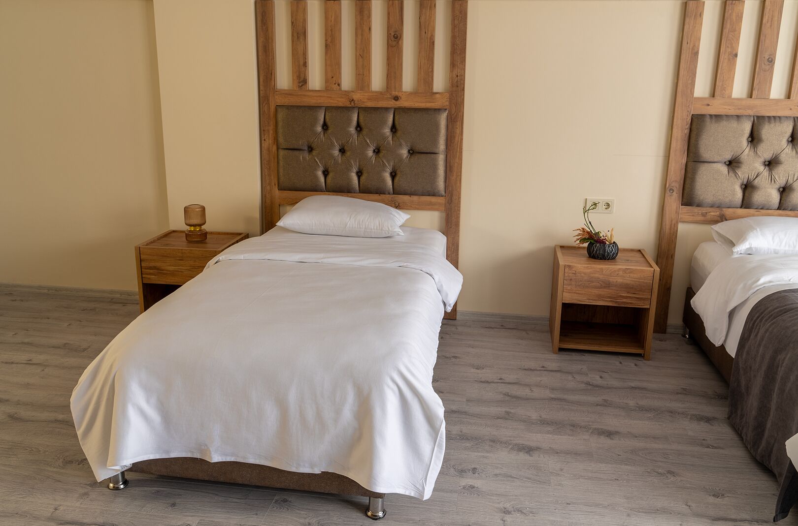 A bedroom with two beds, wooden headboards, and bedside tables with lamps.