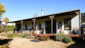 A single-story building with a covered porch, large windows, and a chimney. - Sutton Lodge (Daylesford)
