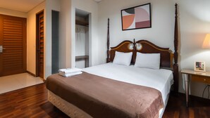 Una habitación de hotel con una cama grande, un armario y una mesita de noche.