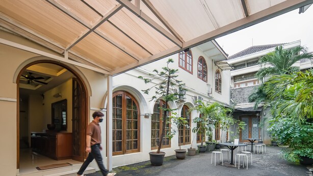 Un patio cubierto con arcos, plantas en macetas y mesas al aire libre.