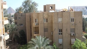Un edificio a più piani con antenne paraboliche, condizionatori d'aria e una piramide sullo sfondo.