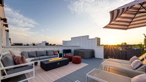 A rooftop terrace with a modern outdoor seating area, including a sofa set, a fire pit, and lounge chairs. - Wildflower - Rooftop Hot Tub - Game Room (Nashville)