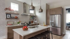A modern kitchen with a central island, stainless steel appliances, and pendant lighting. - Wildflower - Rooftop Hot Tub - Game Room (Nashville)